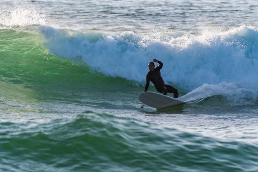 Long boarder surfing the waves at sunset in Portugal.