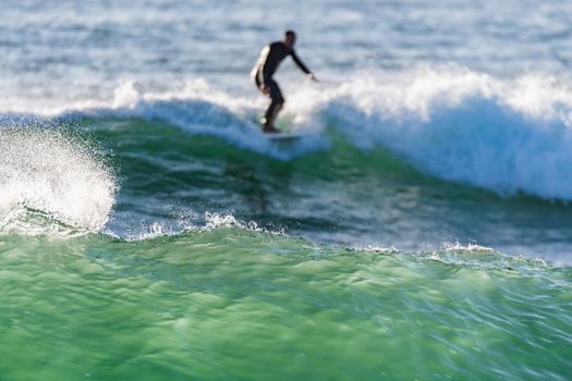 Long boarder surfing the waves at sunset in Portugal.