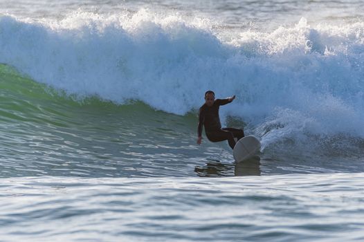 Long boarder surfing the waves at sunset in Portugal.