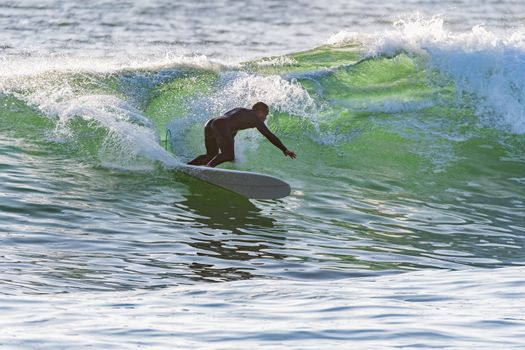 Long boarder surfing the waves at sunset in Portugal.