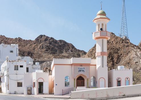 Small mosque in a typical Muscat neighbourhood with a rocky hill in the background in Muscat, Oman.