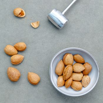 Almonds kernels and whole almonds on concrete background. Whole and chopped almond on concrete background. almond kernels and nutcracker. Selective focus depth of field.