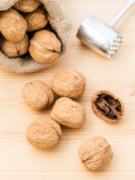 Walnuts kernels and whole walnuts on wooden background. Whole and chopped walnuts on wooden background. Walnuts kernels and nutcracker. Selective focus depth of field.