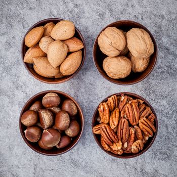 Whole almonds,whole walnuts ,whole hazelnut and pecan nuts in wooden bowl setup with stone background.  