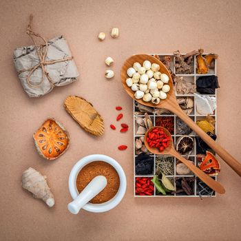 Alternative health care dried various Chinese herbs in wooden box and herbs capsule in wooden spoon with mortar on old wooden background.