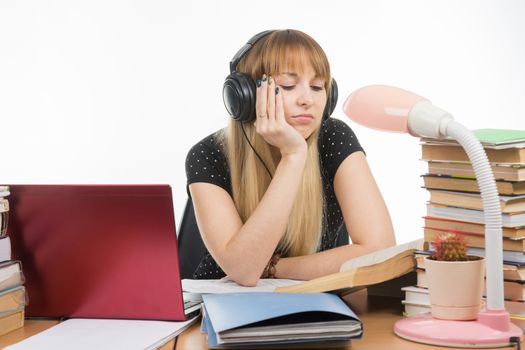 Student falling asleep reading a reference book