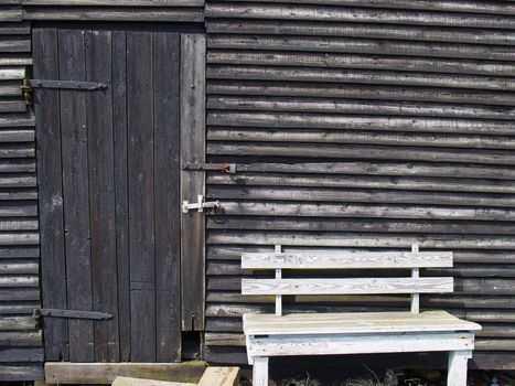 Old vintage rustic wooden house with a bench by the door