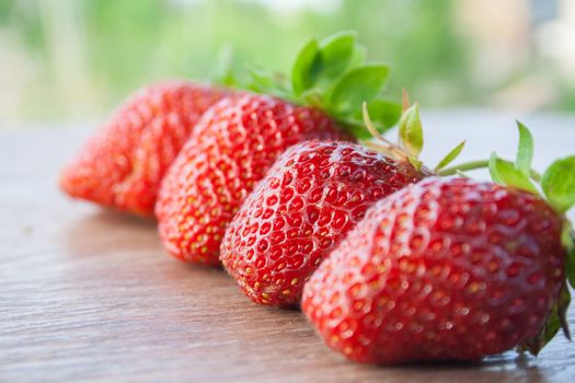 four strawberries in a row, focusing on the second