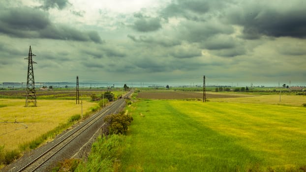 A horizontal shot of railroad tracks extending to the horizon on a cloudy day