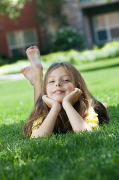 portrait of little girl laying on the grass in summer environment