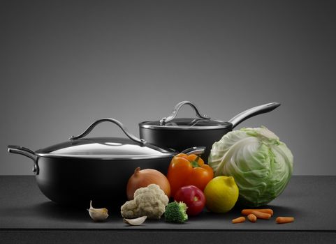 close up view of nice cookware set with some vegetables on grey back