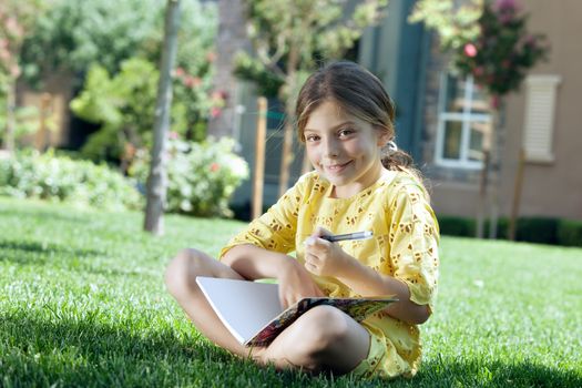 portrait of little girl studying on the grass in summer environment