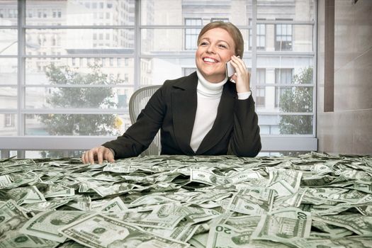 portrait of young woman sitting behind the table full of cash