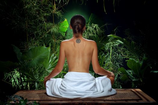 View of nice young woman meditating in spa environment
