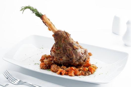 Plate with roast leg of lamb, vegetables and rosemary on white back