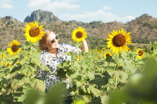 portrait of young smiling happy  woman getting through the sunflower field