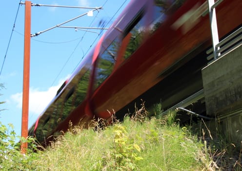 Fast moving red train with grass and blue sky
