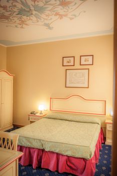 View of an hotel room, desk and bed. Classic style, decorated roof. Old palace.