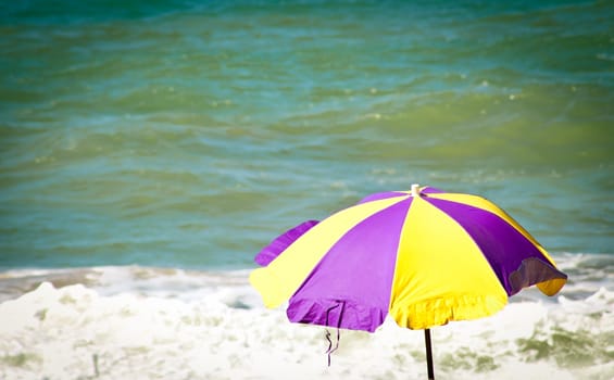 High section of yellow and purple parasol against sea