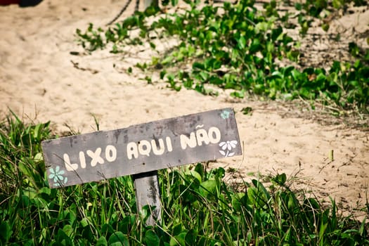Wooden sign on beach entrance saying do not litter here