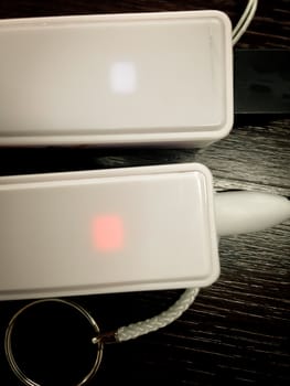 Two portable white battery chargers on wooden table