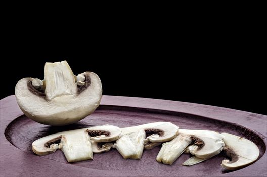 Raw sliced mushrooms and half on the Board, isolated on black background