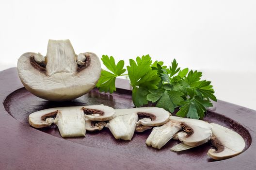 Raw sliced mushrooms, half and parsley, are on the Board.