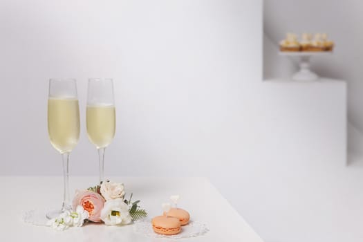 Two glasses with champagne, boutonniere with roses and cookies