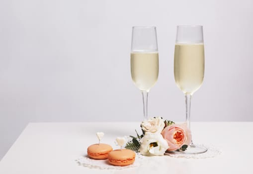 Two glasses with champagne, boutonniere with roses and cookies