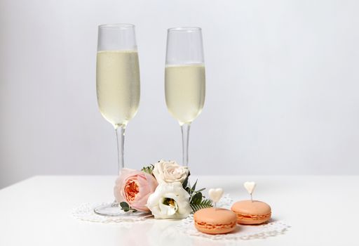 Two glasses with champagne, boutonniere with roses and cookies