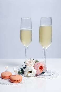 Two glasses with champagne, boutonniere with roses and cookies