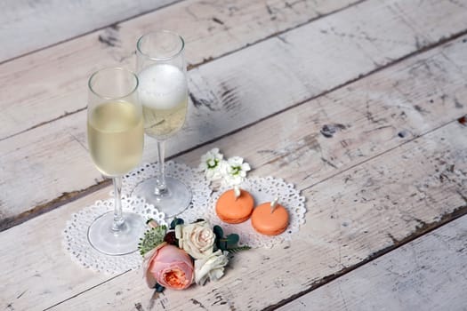 Two glasses with champagne, boutonniere with roses and cookies