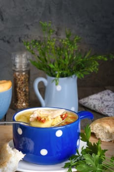 Soup with lentils and chicken, in a blue Cup. The soup in the spoon, bread, spices and parsley