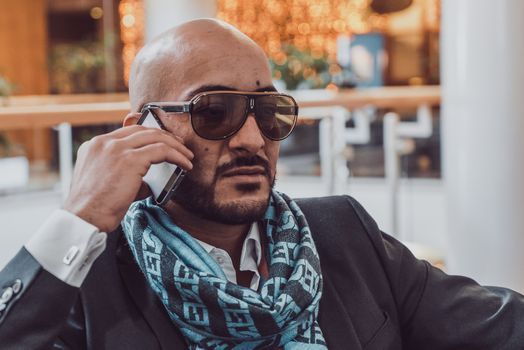 Arab businessman talking on mobile phone at a shopping center