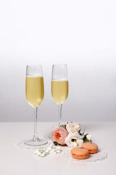 Two glasses with champagne, boutonniere with roses and cookies