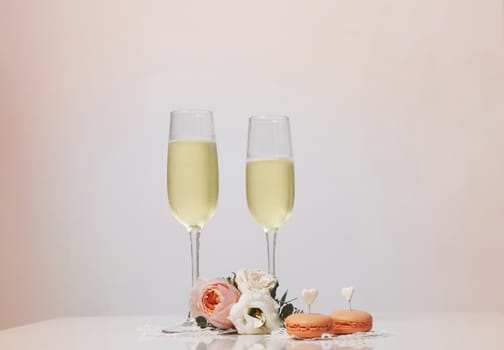 Two glasses with champagne, boutonniere with roses and cookies