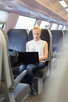 Businesswoman sitting and traveling by train working on laptop.