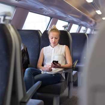 Woman workin on smart phone while traveling by train. Business travel concept.