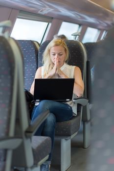 Businesswoman sitting and traveling by train working on laptop.