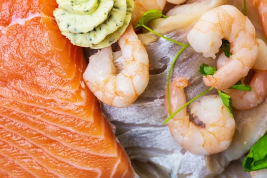Various raw fish species as fillets like salmon, cod and shrimp.