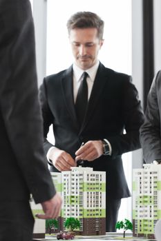 Business meeting of architects and investors looking at model of residential quarter houses