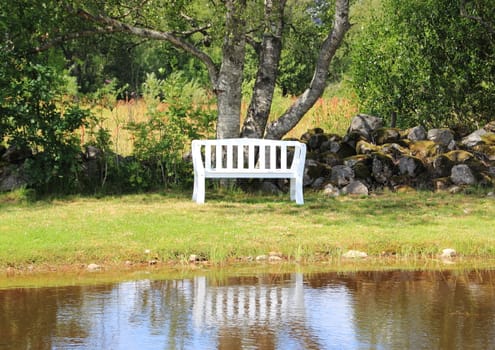 White bench at lake with water reflection