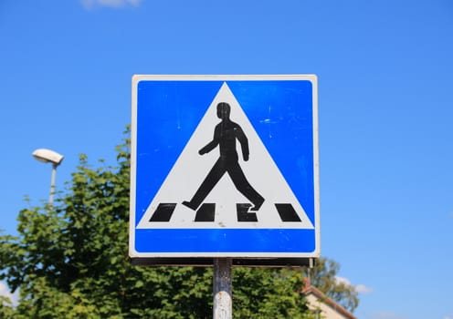 Pedestrian sign with blue sky and tree background