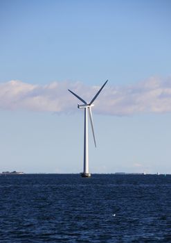 Single sea windmill with dark blue water and clouds