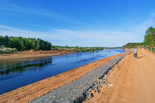 Preparation of the river bank near village for protection against a flood.