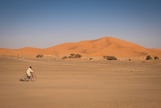 Hassilabied, Morocco - January 19th, 2016: Man riding on a bike in Hassilabied. Hassilabied is a popular tourist destination as a starting point of Sahara Desert excursions.