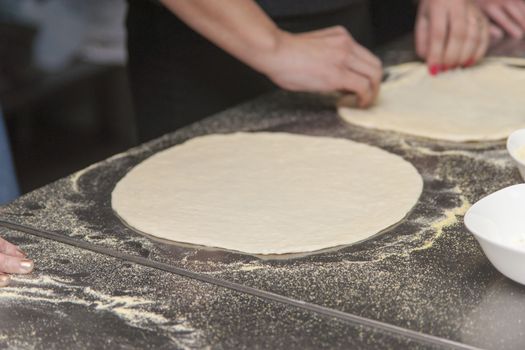 Woman chef with raw dough. Young female in uniform preparing bread dough on table.