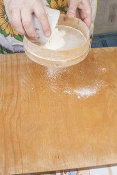 Women's hands preparing flour before baking pie.