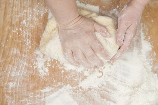 Women's hands preparing fresh yeast dough on wooden table