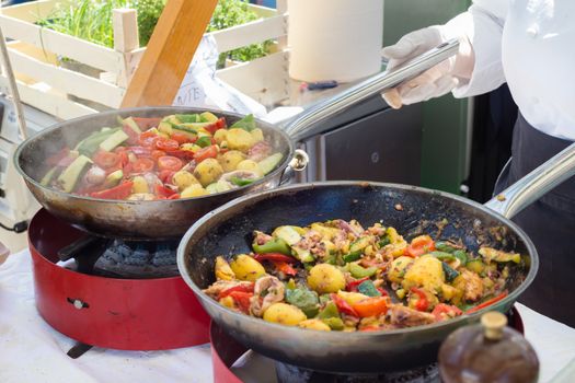 Cheff cooking traditional Mediterranean octopus with potatoes and vegetable on street stall on international street food festival of Odprta kuhna, Open kitchen event, in Ljubljana, Slovenia.